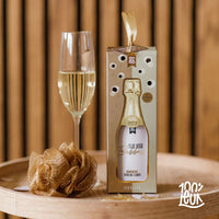 De showergel met showerpuf op een dienblad samen met een glas champagne met een houten achtergrond.