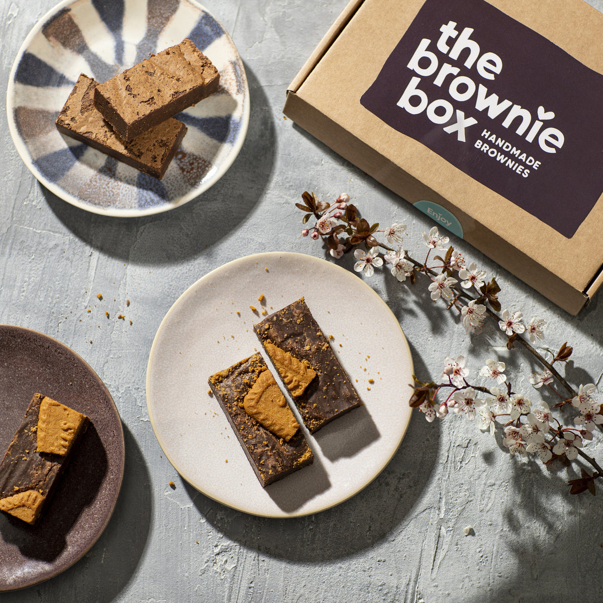Vegan Speculoos Brownies op bordje met rustige achtergrond en The Brownie Box verpakking