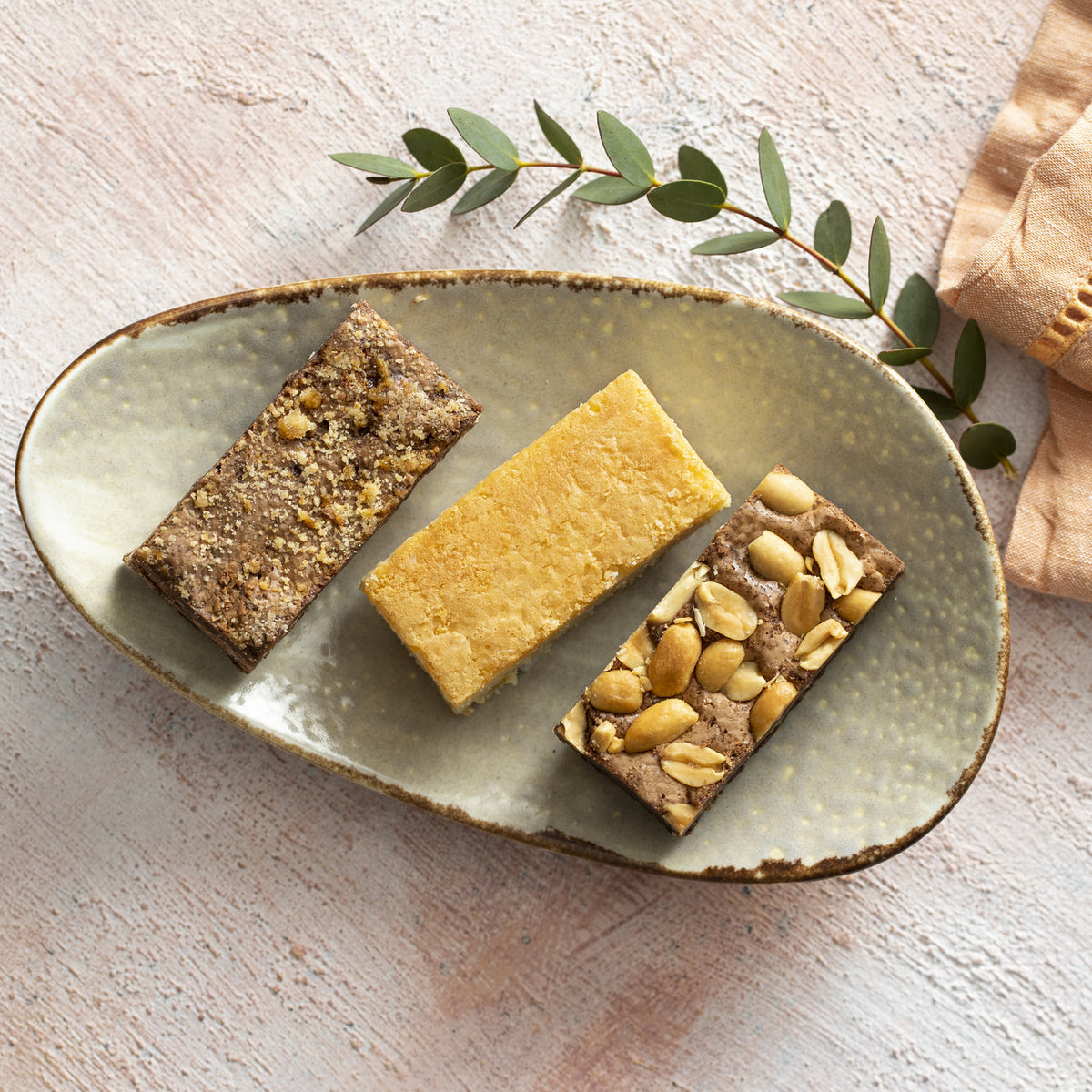 kokos blondie, karamel zeezout brownie en walnoten brownie op bordje met rustige achtergrond en servetje