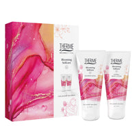 Therme Blooming Selfcare geschenkset met Shower Satin douchegel en Hydra+ Body Lotion, naast een roze cadeauverpakking met bloemendessin. Een verzorgingscadeau voor een ontspannen momentje voor jezelf.